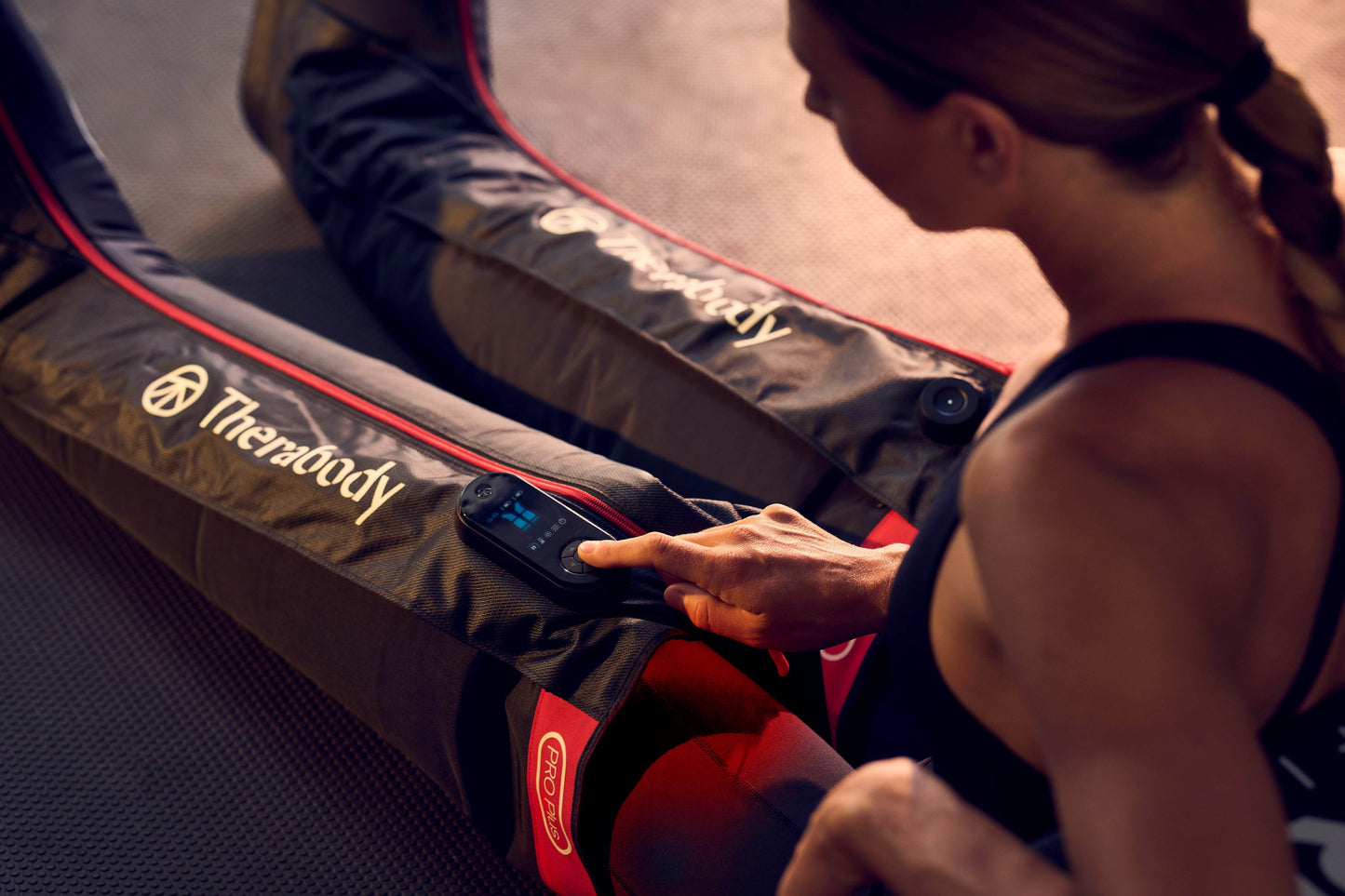 Female athlete using Recovery Boots with compression massage technology from Therabody in a gym
