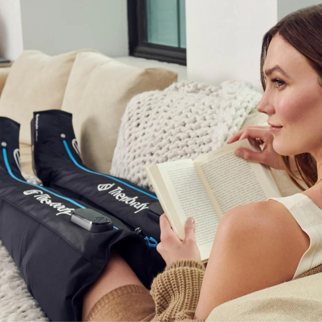 Woman using recovery boots in her home while reading a book