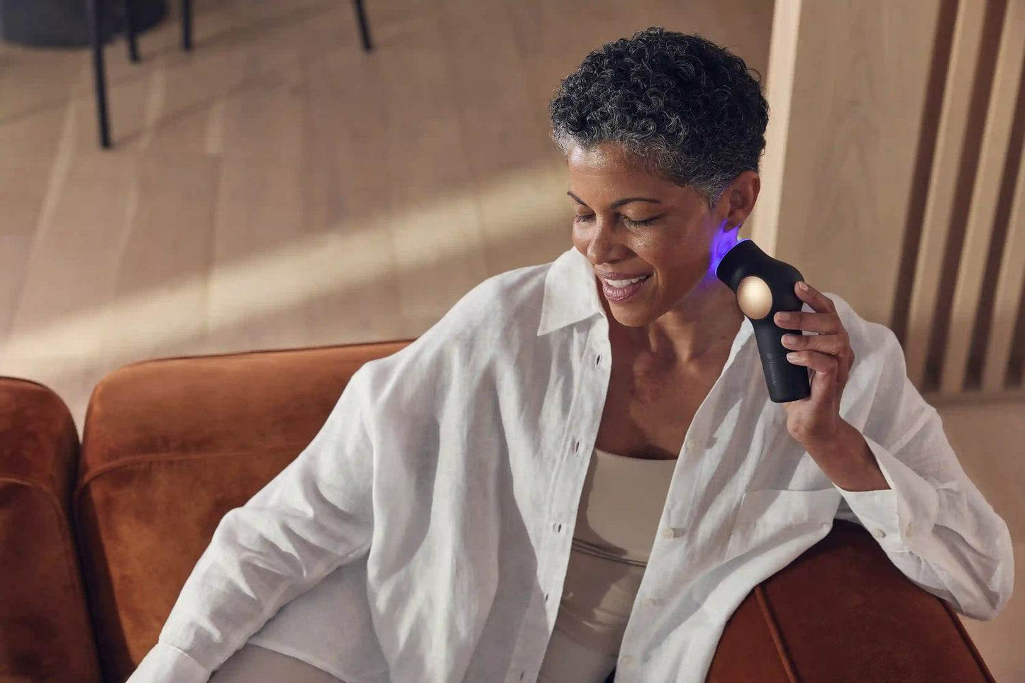 Woman sitting on a couch using a handheld electronic device.